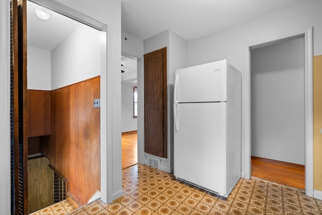 kitchen with freestanding refrigerator, visible vents, baseboards, and wood finished floors