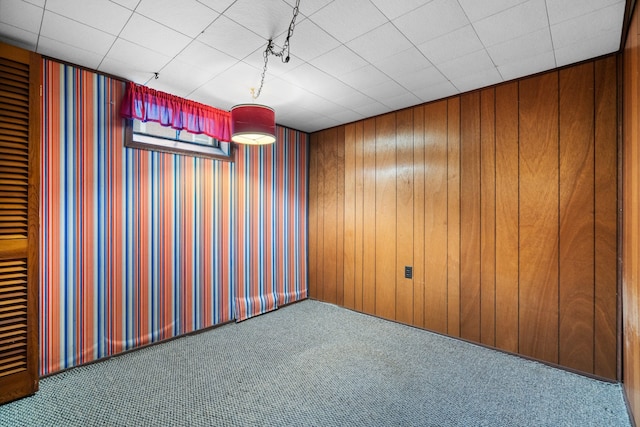 carpeted empty room featuring wood walls