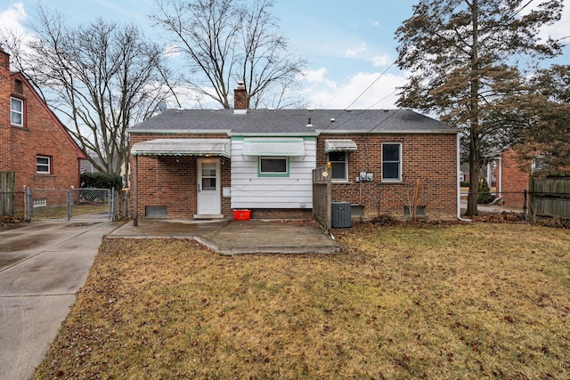 rear view of house with a chimney, a gate, fence, a yard, and brick siding