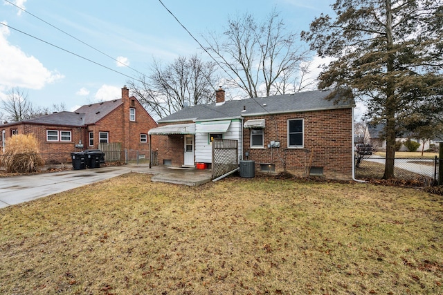 back of property with brick siding, a yard, a chimney, central air condition unit, and fence