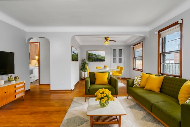 living room with baseboards, arched walkways, ceiling fan, and wood finished floors