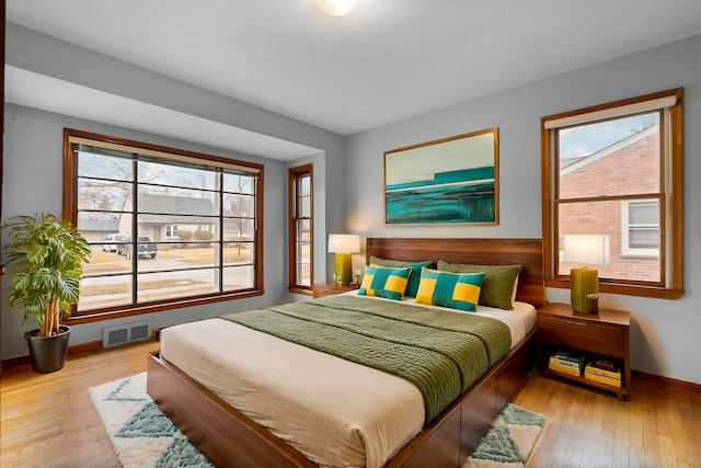 bedroom featuring wood-type flooring, visible vents, and baseboards