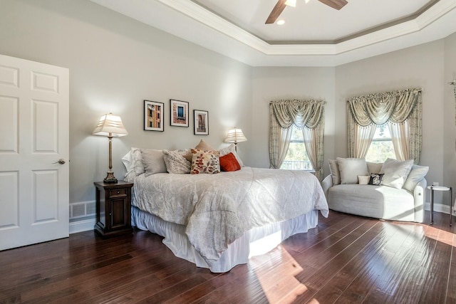 bedroom with baseboards, crown molding, dark wood finished floors, a ceiling fan, and a tray ceiling