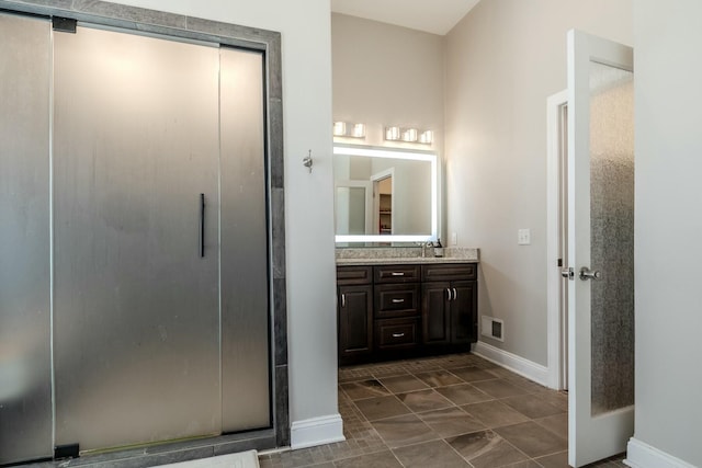 full bath with a sink, visible vents, baseboards, a stall shower, and double vanity