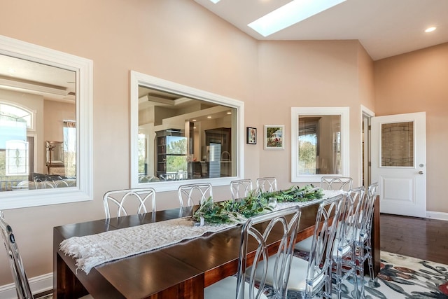 dining space featuring a wealth of natural light, baseboards, wood finished floors, and a skylight