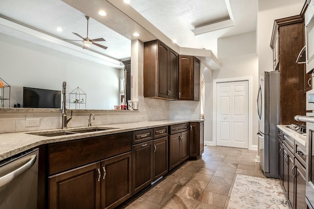 kitchen featuring dark brown cabinets, tasteful backsplash, appliances with stainless steel finishes, and a sink