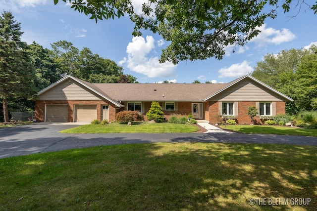 ranch-style home with aphalt driveway, a front yard, brick siding, and an attached garage