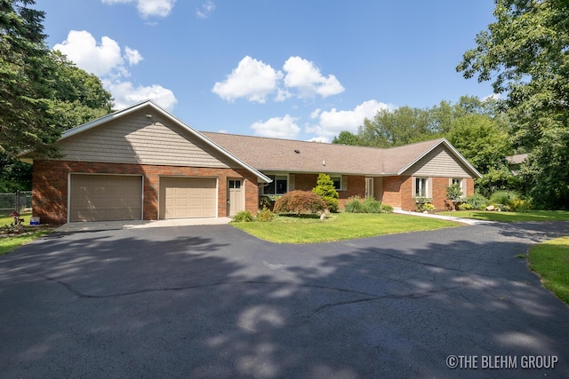 ranch-style home featuring aphalt driveway, a front lawn, an attached garage, and brick siding