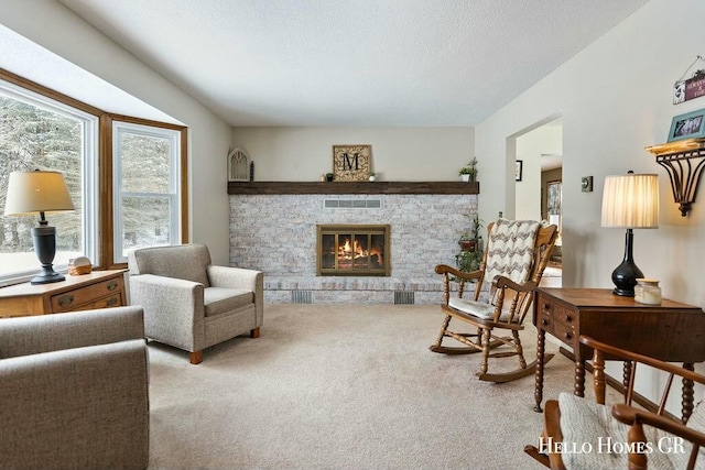 sitting room with light colored carpet, visible vents, a fireplace, and a textured ceiling