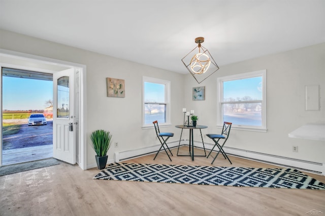 dining space featuring baseboards, baseboard heating, a healthy amount of sunlight, and wood finished floors