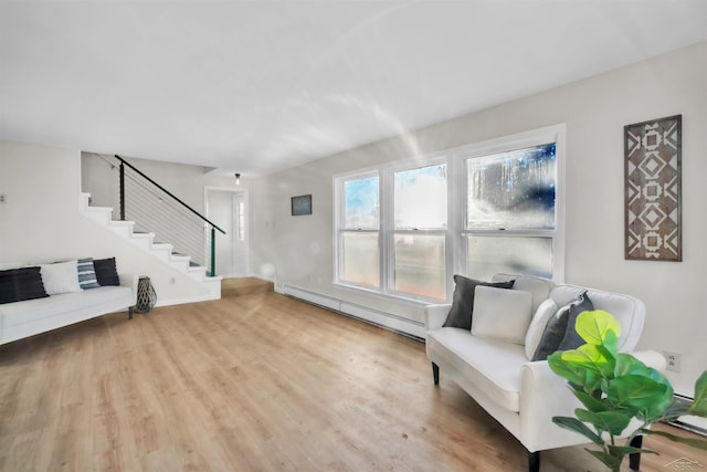 living area with light wood finished floors, stairs, and a baseboard heating unit