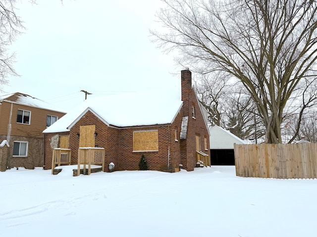 view of front of house featuring a chimney, a detached garage, fence, and brick siding