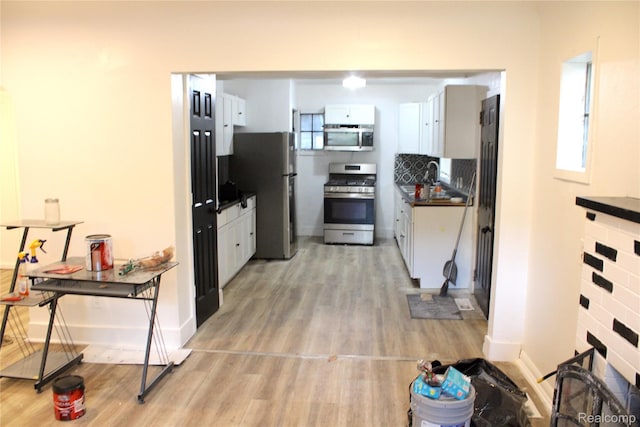 1629 Seminole St, Flint, MI 48503 - kitchen featuring appliances with stainless steel finishes, dark countertops, light wood-type flooring, and white cabinetry