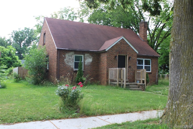 1629 Seminole St, Flint, MI 48503 - view of front of house featuring a chimney, brick siding, a front yard, and a shingled roof