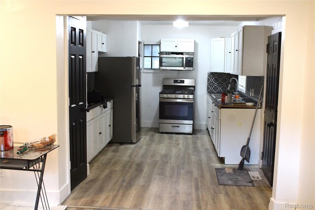 1629 Seminole St, Flint, MI 48503 - kitchen with stainless steel appliances, light wood-style flooring, dark countertops, and white cabinetry