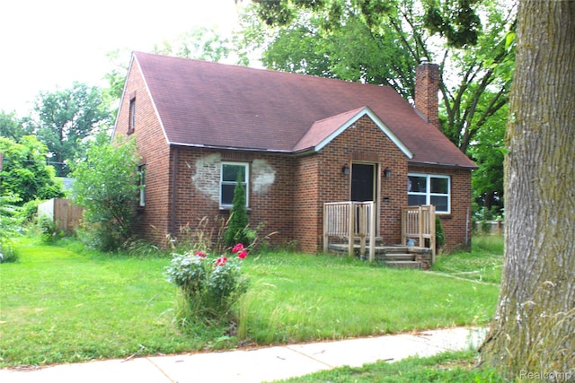 1629 Seminole St, Flint, MI 48503 - view of front of house with a chimney, brick siding, a front yard, and roof with shingles