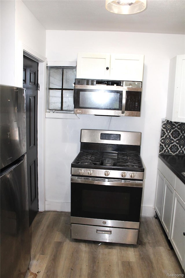 1629 Seminole St, Flint, MI 48503 - kitchen with appliances with stainless steel finishes, white cabinetry, dark wood-style flooring, and dark countertops