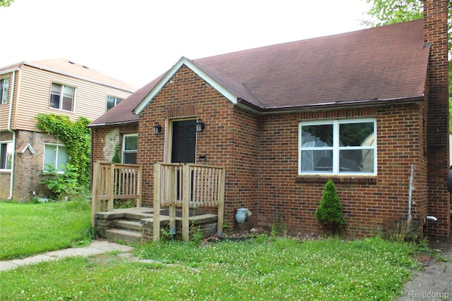 1629 Seminole St, Flint, MI 48503 - view of front of property with brick siding, a front yard, a chimney, and roof with shingles