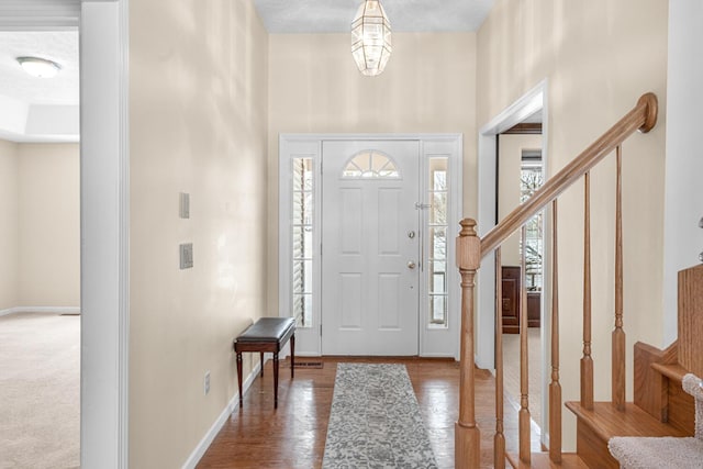 entrance foyer with baseboards, plenty of natural light, wood finished floors, and stairway