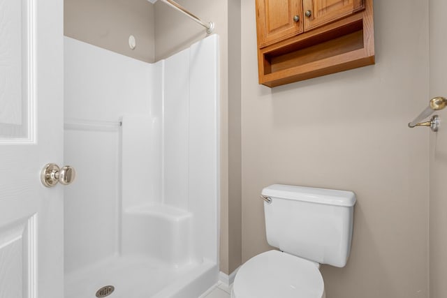 bathroom featuring a shower stall and toilet