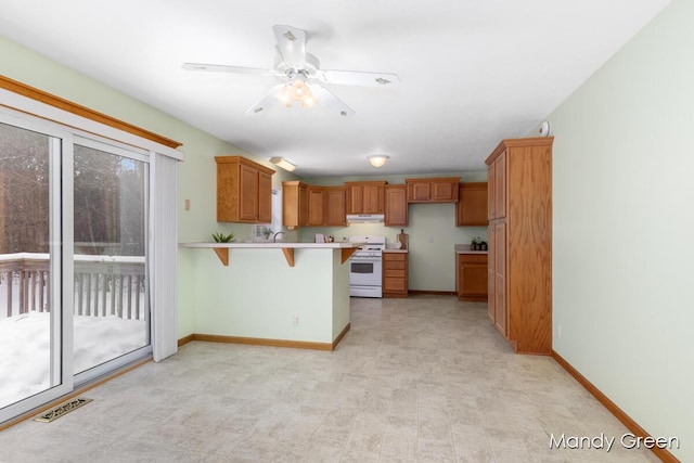 kitchen with visible vents, brown cabinets, a breakfast bar area, gas range gas stove, and light countertops