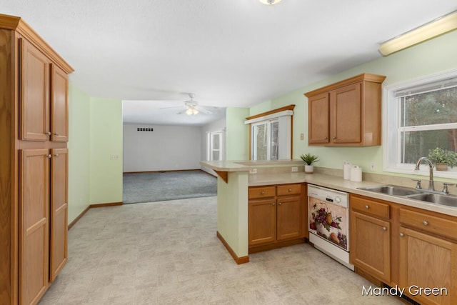 kitchen featuring open floor plan, white dishwasher, a sink, light countertops, and a peninsula