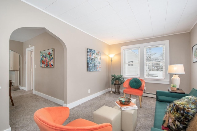 sitting room with arched walkways, light colored carpet, baseboard heating, and baseboards