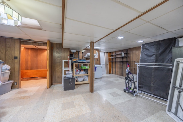 finished below grade area featuring wooden walls, a paneled ceiling, and tile patterned floors