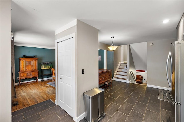 interior space featuring pendant lighting, visible vents, dark wood-type flooring, freestanding refrigerator, and baseboards