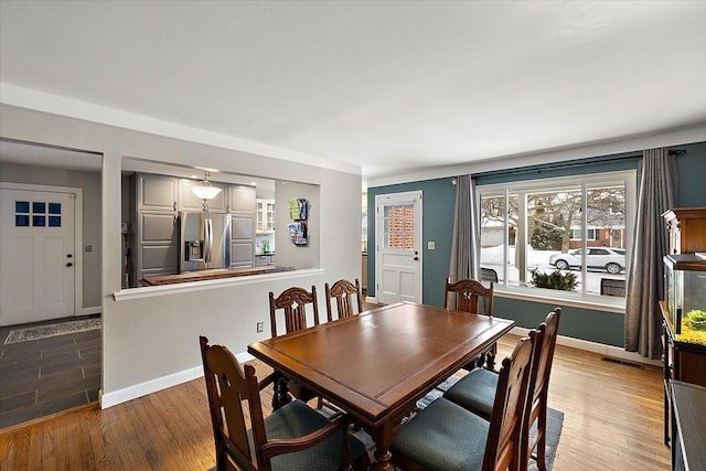 dining space featuring wood finished floors, visible vents, and baseboards