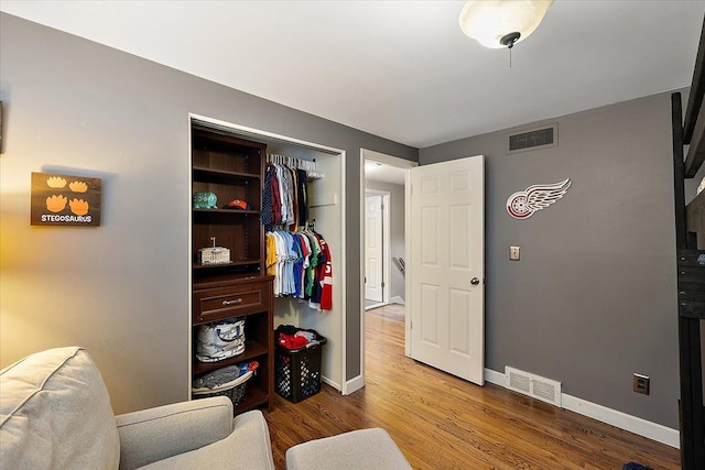 living area with baseboards, visible vents, and wood finished floors