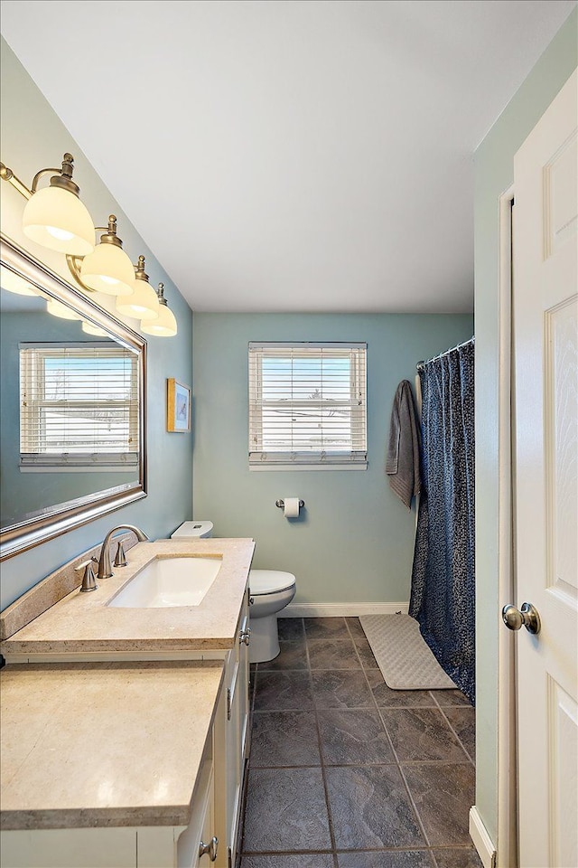 bathroom featuring toilet, vanity, and baseboards