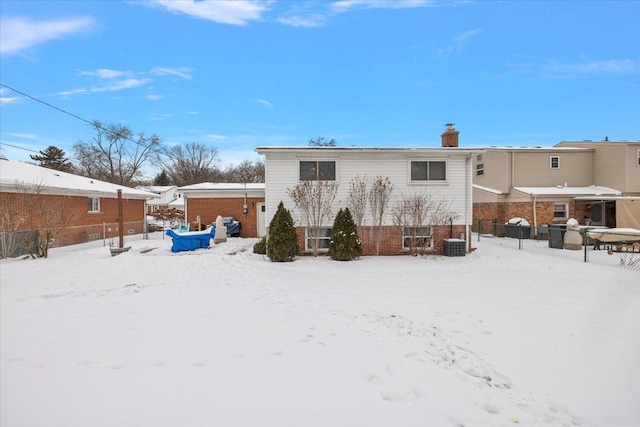 snow covered back of property with brick siding and a chimney