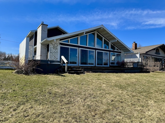 back of property with a lawn, a sunroom, and a chimney