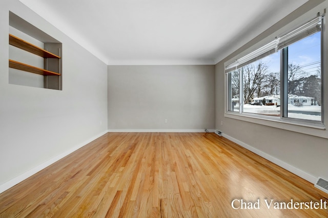 unfurnished room featuring crown molding, baseboards, and light wood finished floors