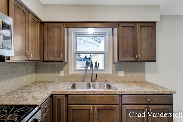 kitchen featuring a sink, light countertops, stainless steel microwave, and decorative backsplash