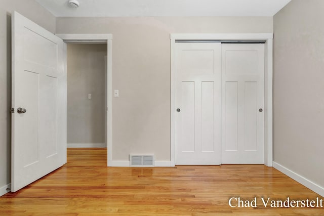 unfurnished bedroom featuring visible vents, a closet, baseboards, and light wood finished floors