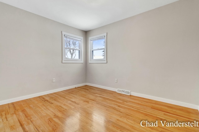 spare room with baseboards, visible vents, and wood finished floors