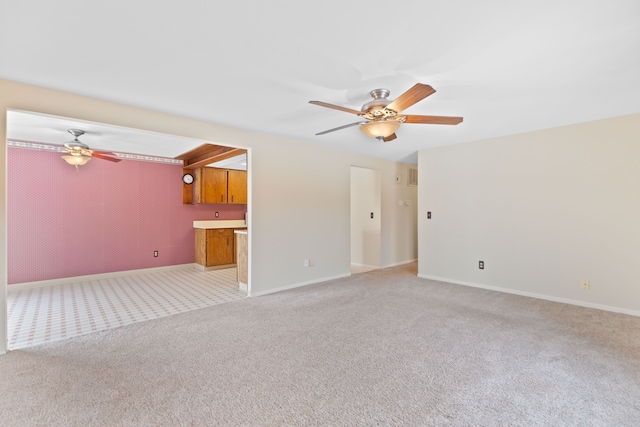 unfurnished living room featuring baseboards, a ceiling fan, and light colored carpet