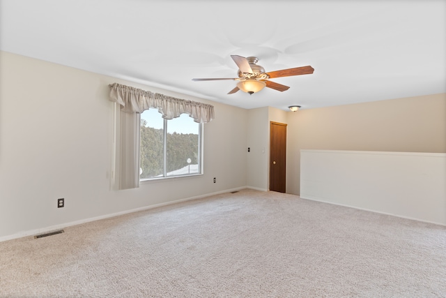 carpeted spare room with a ceiling fan, visible vents, and baseboards