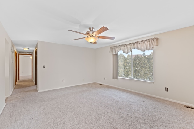 unfurnished room featuring light carpet, baseboards, visible vents, and a ceiling fan