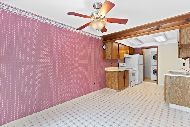 kitchen with white appliances, a sink, light countertops, brown cabinetry, and stacked washer and clothes dryer