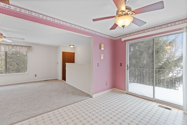 empty room with light colored carpet, visible vents, a ceiling fan, baseboards, and wallpapered walls