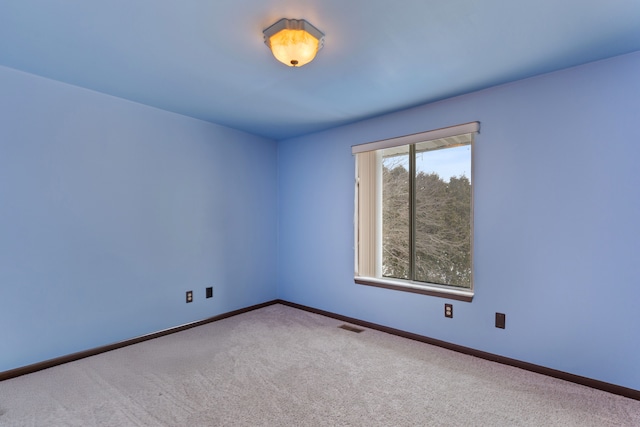 empty room featuring carpet, visible vents, and baseboards