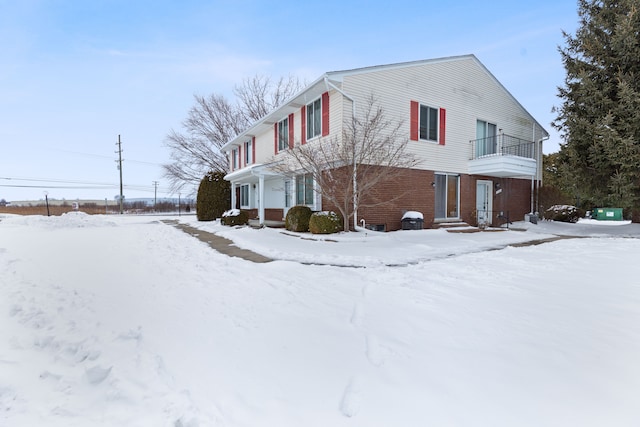 view of front of home featuring a garage, brick siding, and a balcony