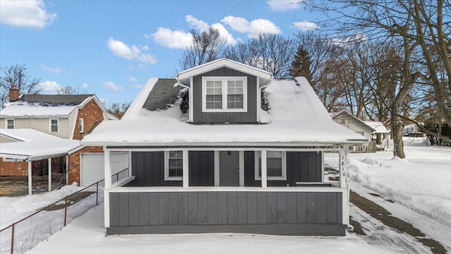 view of front facade with board and batten siding, an attached garage, and fence