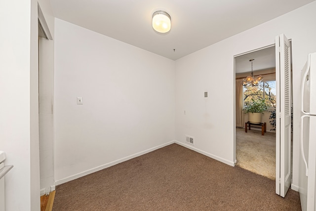 unfurnished bedroom with visible vents, a chandelier, baseboards, freestanding refrigerator, and dark carpet