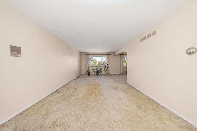 empty room featuring light carpet, baseboards, and visible vents