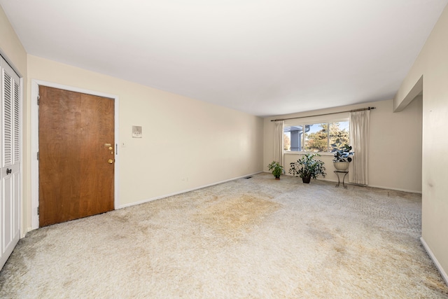 unfurnished room featuring baseboards and light colored carpet