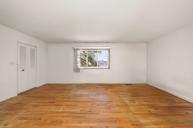 empty room with light wood-type flooring, baseboards, and visible vents